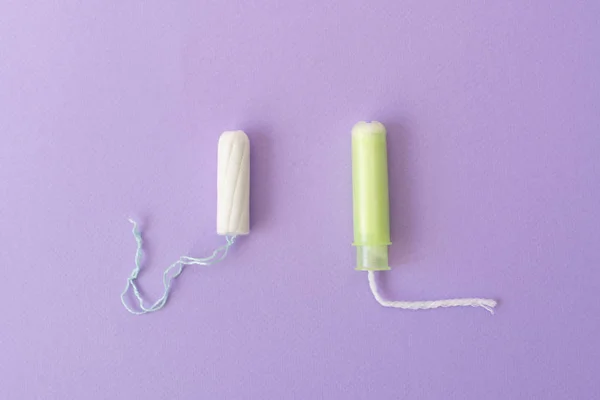 Dois tampões de algodão com aplicador verde claro e sem aplicador em fundo violeta. Tipos higiénicos de tampões. Menstruação, proteção, conceito de comparação, flat lay, espaço de cópia, vista superior — Fotografia de Stock