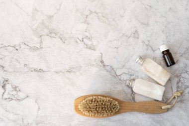 Kozmetoloji, damatlık, spa kozmetik ürünleri, güzellik ve vücut bakımı konsepti. Masaj yumuşak fırça, vücut kremi ve mermer arka plan üzerinde uçucu yağ. Üst görünüm, metin için kopya alanı