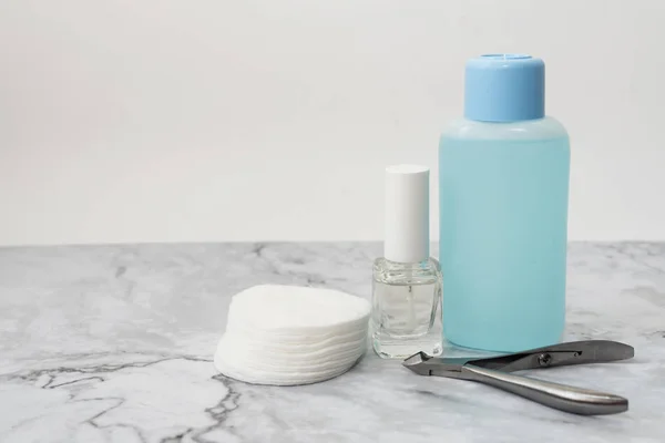 Yumuşak mermer yüzeyüzerinde manucure tırnak bakım ürünleri seti. Renksiz sıkılaşma oje ile Cam şişe, tırnak vernik sökücü ve pamuk pedleri ile plastik şişe. Ön görüş. Metin için alan kopyalama