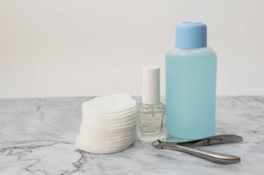Yumuşak mermer yüzeyüzerinde manucure tırnak bakım ürünleri seti. Renksiz sıkılaşma oje ile Cam şişe, tırnak vernik sökücü ve pamuk pedleri ile plastik şişe. Ön görüş. Metin için alan kopyalama