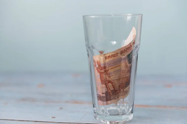 Rus beş bin rublelik banknot, tahta bir masanın üzerindeki bardakta ve mavi bir arka planda toplandı. Yer kopyala, tasarruf kavramı