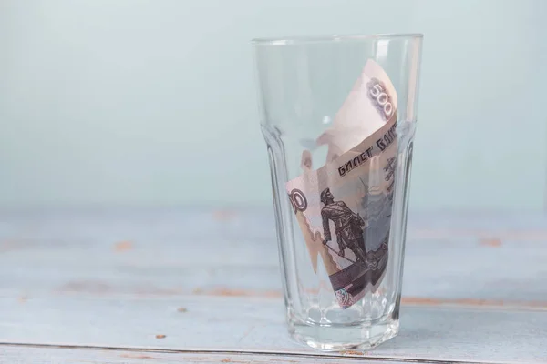 Rus 500 rublelik banknot, ahşap bir masanın üzerindeki bardakta ve mavi bir arka planda toplanmış. Yer kopyala, tasarruf kavramı