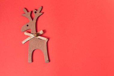Kırmızı arka planda tahta geyik süslemesi. Noel konsepti ve yeni yıl süsü. Üst görünüm, alanı kopyala