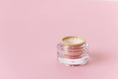 Pembe tarafsız arka planda yüz kremi olan cam parlak güzellik kavanozu. Yüz bakımı için organik doğal ürün. Üst Manzara. Düz yatıyordu. Kozmetik, cilt bakımı, güzellik, vücut tedavisi konsepti.