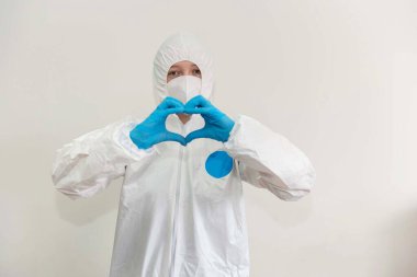 Beyaz koruyucu giysili doktor, tıbbi maske ve mavi eldiven kalp belirtileri gösteriyor. Hastalara aşkı ifade etme kavramı. Salgın, Coronavirus covid 19 salgını. Boşluğu Kopyala