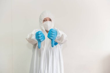 Beyaz koruyucu giysili doktor, tıbbi maske ve mavi eldiven bir baş parmak göstermiyor. Salgın, Coronavirus covid 19 salgını. Boşluğu Kopyala