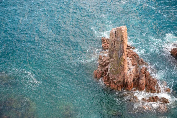Uçurumun tepesinden bakan güzel bir deniz ve kaya. Atardamar gözünden çeşitli deniz köpüğü dalgaları. Gök mavisi deniz, temiz şeffaf su, Primorye, Uzak Doğu, Rusya