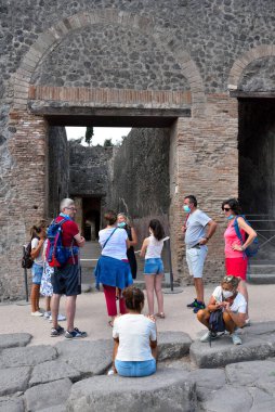 Antik Roma şehrinin kalıntılarında maskeli turist grupları, MS 79 yılında Vesuvius 'un patlaması sonrasında yok edilip küllere gömüldü.