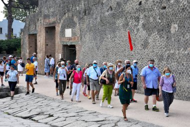 Antik Roma şehrinin kalıntılarında maskeli turist grupları, MS 79 yılında Vesuvius 'un patlaması sonrasında yok edilip küllere gömüldü.
