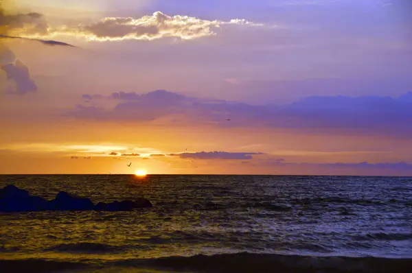 Bir gün batımı kayalar ön planda ve kuş uçuş