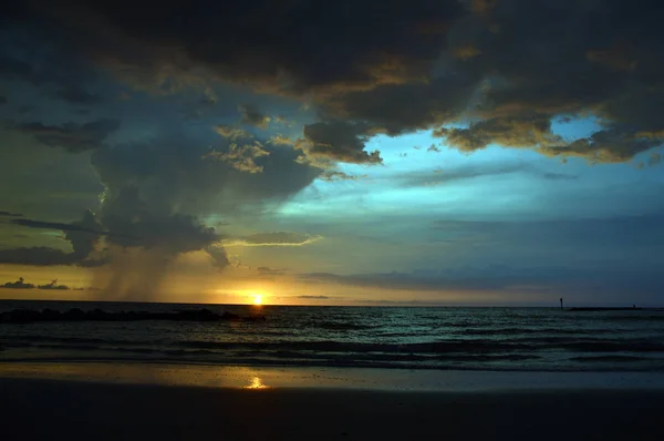 Plaja fırtına bulutları, yağmur mesafe ile bir gün batımı
