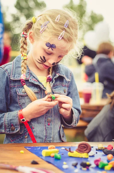 かわいいブロンドの女の子遊び生地で遊んでいるとテーブルの上の図を作成します — ストック写真