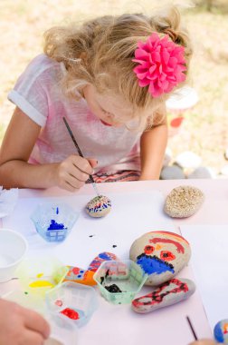 sevimli küçük sarışın çocuk boyama taşlar ile eğleniyor