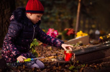 mezarlıkta Tüm Azizler Günü sırasında çocuk yanan mum