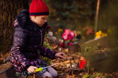 mezarlıkta Tüm Azizler Günü sırasında çocuk yanan mum
