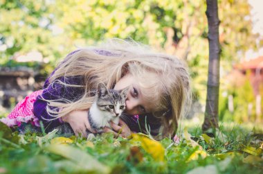 kedi ile güzel sarışın kız ve sonbahar zamanında çim üzerinde birlikte yalan
