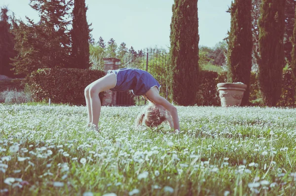 Lány Zöld Rét Virágokkal Teli Akrobatikus Testtartás — Stock Fotó