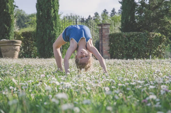 yeşil çayır çiçek tam akrobatik duruş ile kız