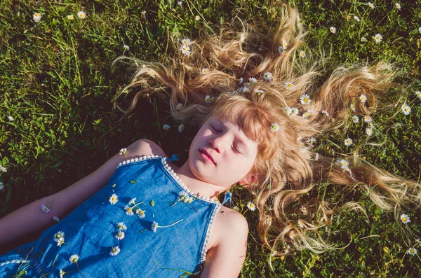 Милая Девушка Длинными Светлыми Волосами Лежит Среди Маргаритки Зеленой Траве — стоковое фото