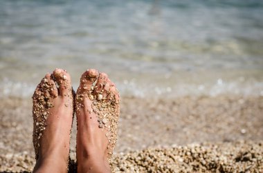 deniz tarafından plajda küçük taşlarla kaplı ayakları görünümü