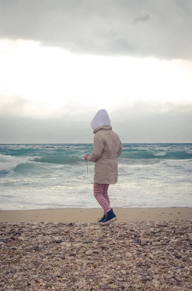 小女孩独自在鹅卵石海滩与波浪形的大海 — 图库照片