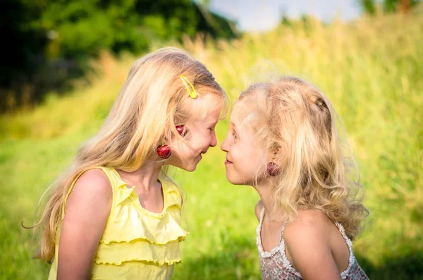 Niños con cerezas en los oídos cara a cara — Foto de Stock