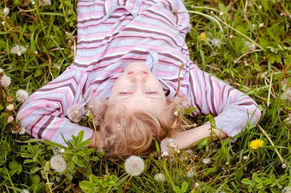 Słodkie dziecko leżące na łące mniszka lekarskiego — Zdjęcie stockowe
