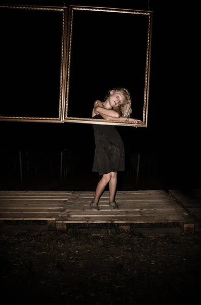 Liten flicka bakom gyllene ram på natten — Stockfoto