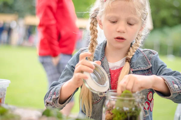 Niño activo llenando vidrio vacío con tierra y plantas —  Fotos de Stock