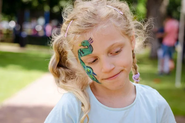 Menina sorridente com pintura facial de pavão — Fotografia de Stock