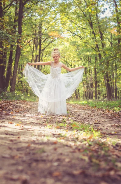 Очаровательный ребенок в длинном белом свадебном платье — стоковое фото