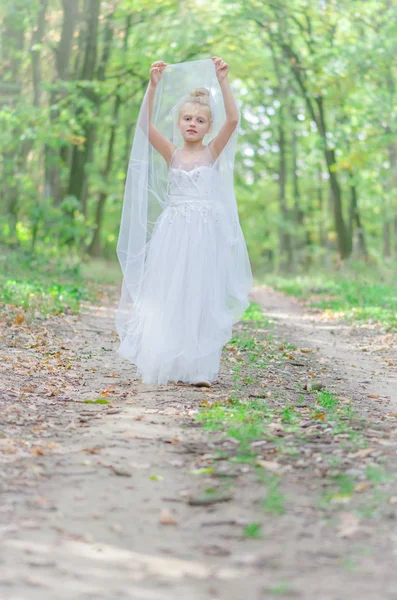 Adorable child in long white wedding dress in dreamy atmosphere — Stock Photo, Image