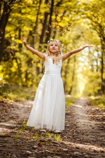 Adorável menina loira com folhas nas mãos em dia ensolarado na floresta mágica — Fotografia de Stock