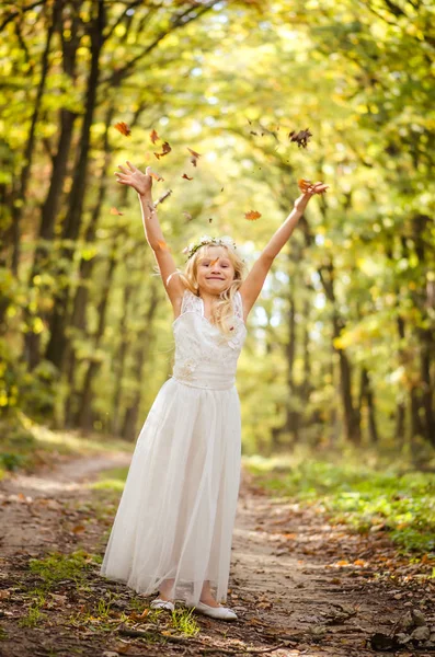Entzückendes blondes Mädchen mit Blättern in den Händen an einem sonnigen Tag im Zauberwald — Stockfoto
