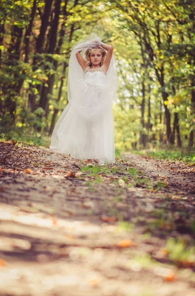 Adorable blond girl walking in sunny day in magical forest — Stock Photo, Image