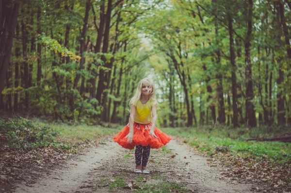 Чарівна блондинка в помаранчевій спідниці в лісі — стокове фото