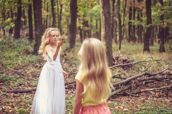 Adorable child in long white wedding dress with butterfly in hands — Stock Photo, Image