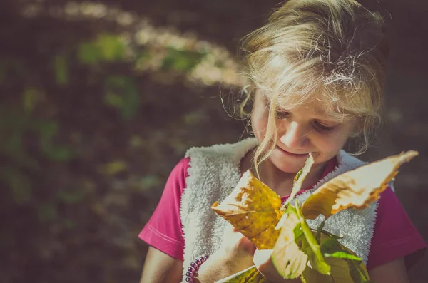 Schattig blond meisje met oranje bladeren — Stockfoto