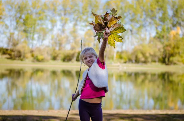 Adorable blond girl with orange leaves — Stock Photo, Image