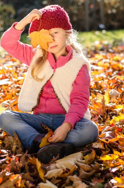 Niedliches Kind, das mit gefallenen bunten Blättern spielt — Stockfoto
