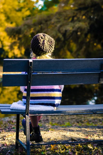 Pequeño niño solitario sentado en el banco solo — Foto de Stock