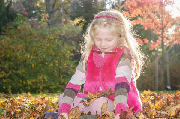 Мила дівчина в золотий годинний час сидить у траві і залишає в чарівному парку — стокове фото