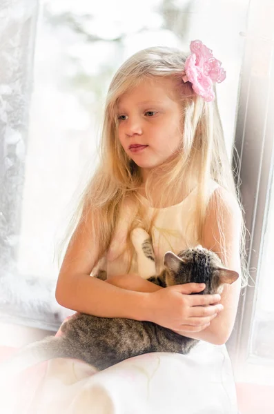 Uzun sarı saçlı küçük kediyi tutan kız. — Stok fotoğraf