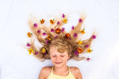 Sevimli, gülümseyen bir çocuk, sağlıklı ve güçlü uzun sarı saçları var. Çiçek fikirleriyle süslenmiş güneş şeklinde.