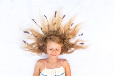 Uzun sarı saçlı, lavanta süslemeli tatlı bir çocuk. Kuşlar tarafından çekilmiş.