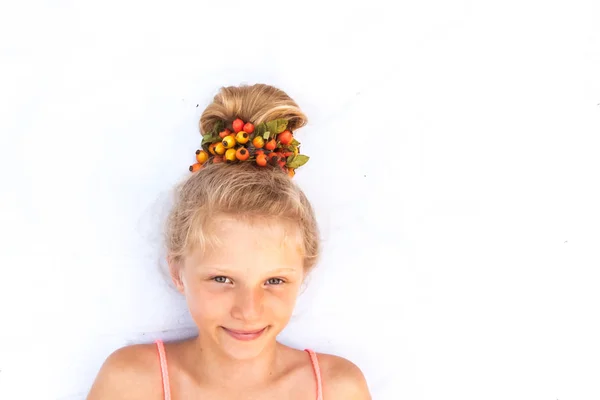Roztomilé usmívající se malé dítě s legrační blond houska zdobené červeným brier bobule kopírovat prostor — Stock fotografie