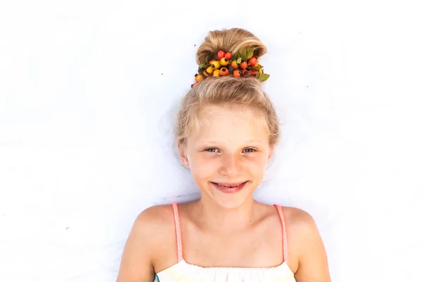Bonito sorrindo pequena criança com engraçado loiro bun decorado com vermelho brier berry copy space — Fotografia de Stock