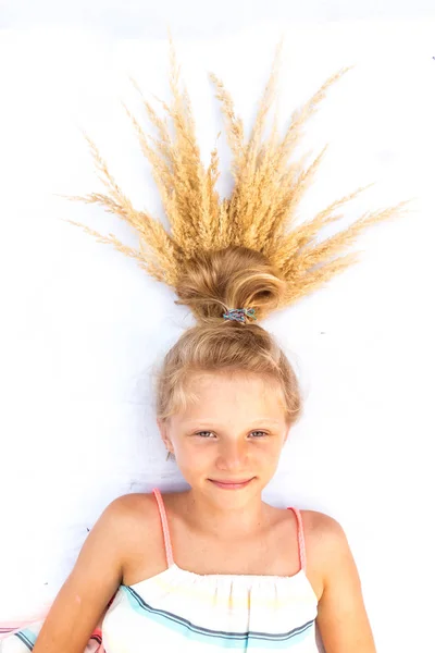 Mignon petit enfant souriant avec un petit pain blond drôle décoré avec pointe dorée mûre de grain de blé — Photo