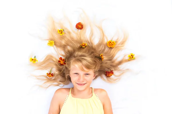 Adorável criança sorridente com cabelos louros longos saudáveis e fortes em forma de sol adornado com flores espaço cópia — Fotografia de Stock