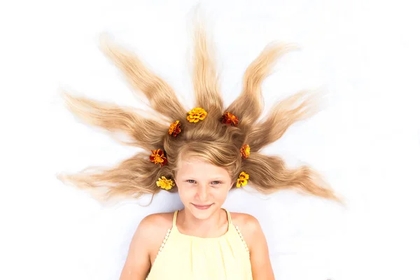 Adorável criança sorridente com cabelos louros longos saudáveis e fortes em forma de sol adornado com flores espaço cópia — Fotografia de Stock